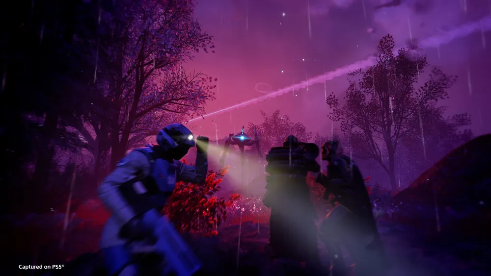 Four Helldivers defend a rocky battlefield against alien creatures.