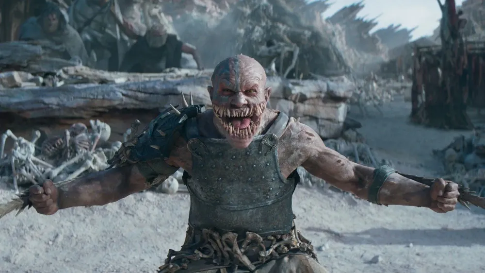 Baraka, the fanged Tarkatan warrior, snarls on a bone-strewn battlefield in Mortal Kombat II.