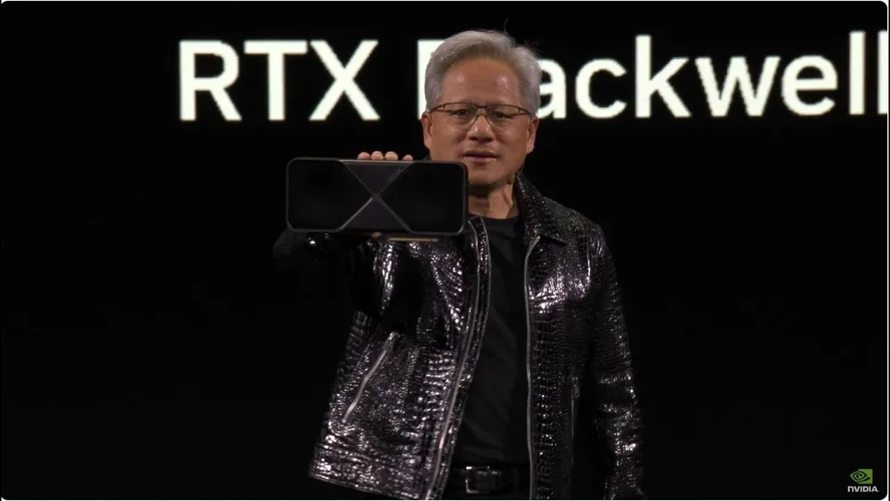 Nvidia CEO Jensen Huang on stage in a black leather jacket, holding up an RTX Blackwell graphics card.