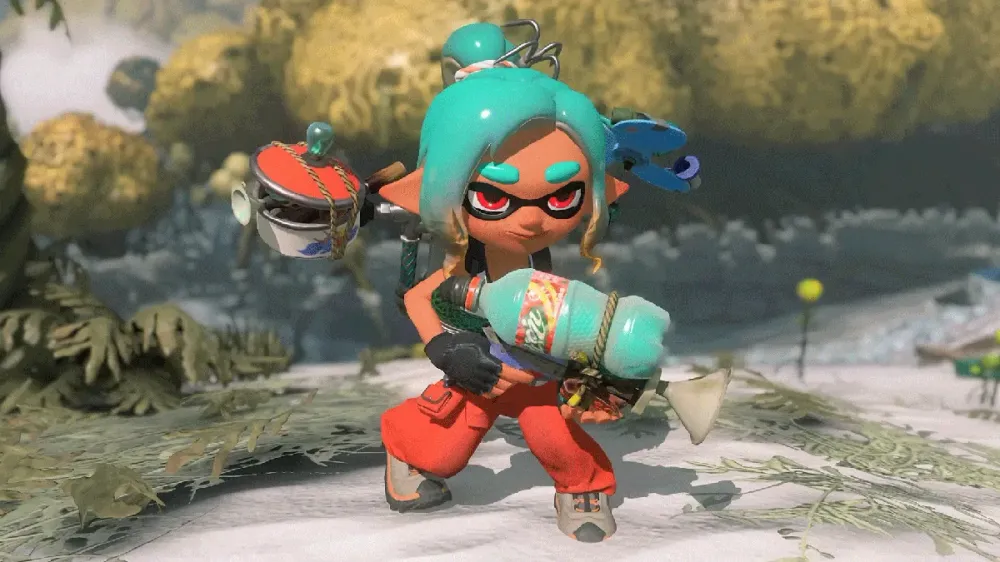 A teal-haired Inkling in orange overalls crouches in a coral-strewn ruin, holding a bottle-shaped weapon with a tambourine-like gadget clipped to the ink tank.